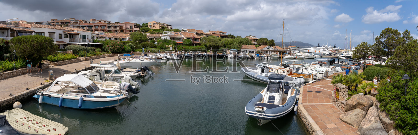 在一个阳光明媚的日子里，在以豪华和富有的游客而闻名的斯梅拉尔达海岸，罗通多港豪华村庄的码头全景，船上有船只和住宅建筑照片摄影图片
