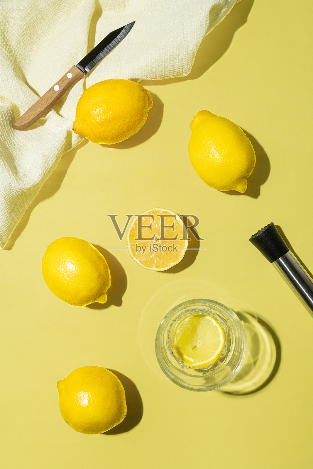 柠檬整片，在黄色背景上用玻璃杯、刀和搅拌机切片。用柠檬制作柠檬水和饮料的概念照片摄影图片