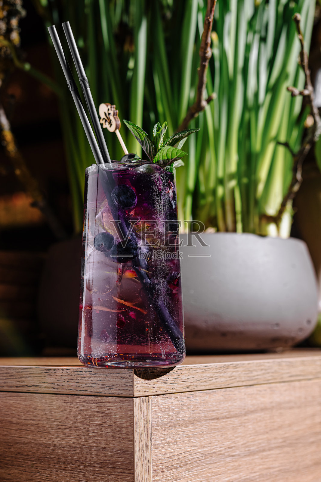 清爽的紫色鸡尾酒站在酒吧与植物的背景照片摄影图片