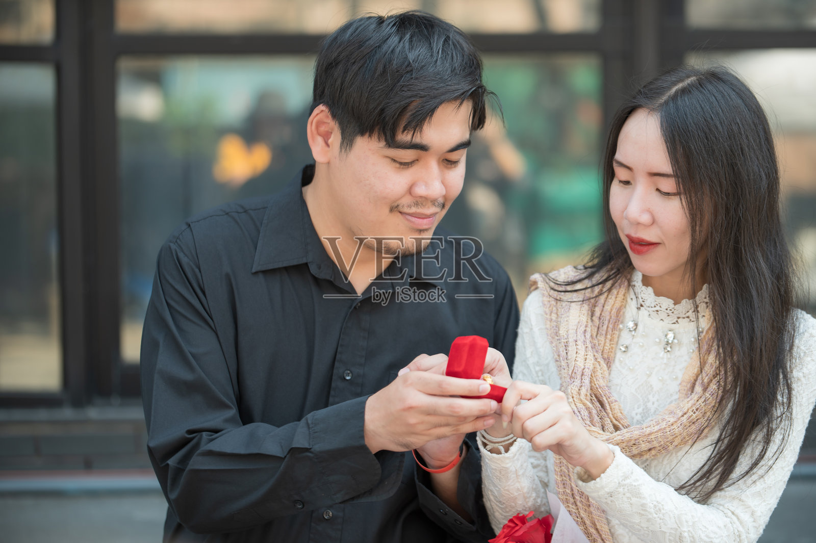 亚洲男子出人意料地向女友求婚，浪漫的男子带着结婚戒指向女子求婚，一起享受惊喜的订婚照片摄影图片