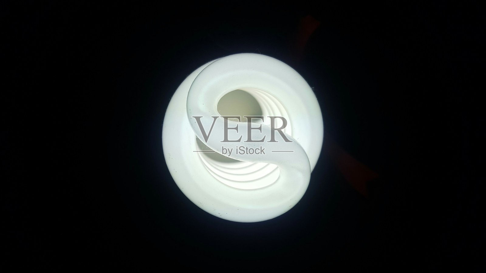正上方的黑色背景照明节能灯泡的镜头照片摄影图片