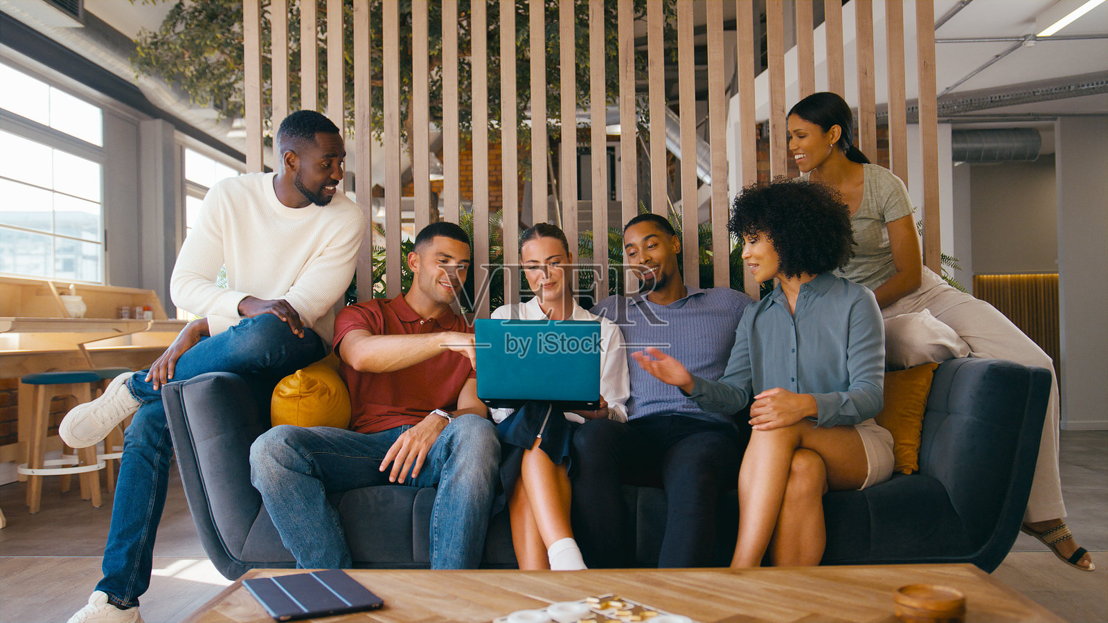 多文化商务团队坐在现代开放式办公室的沙发上，一起用笔记本电脑工作照片摄影图片