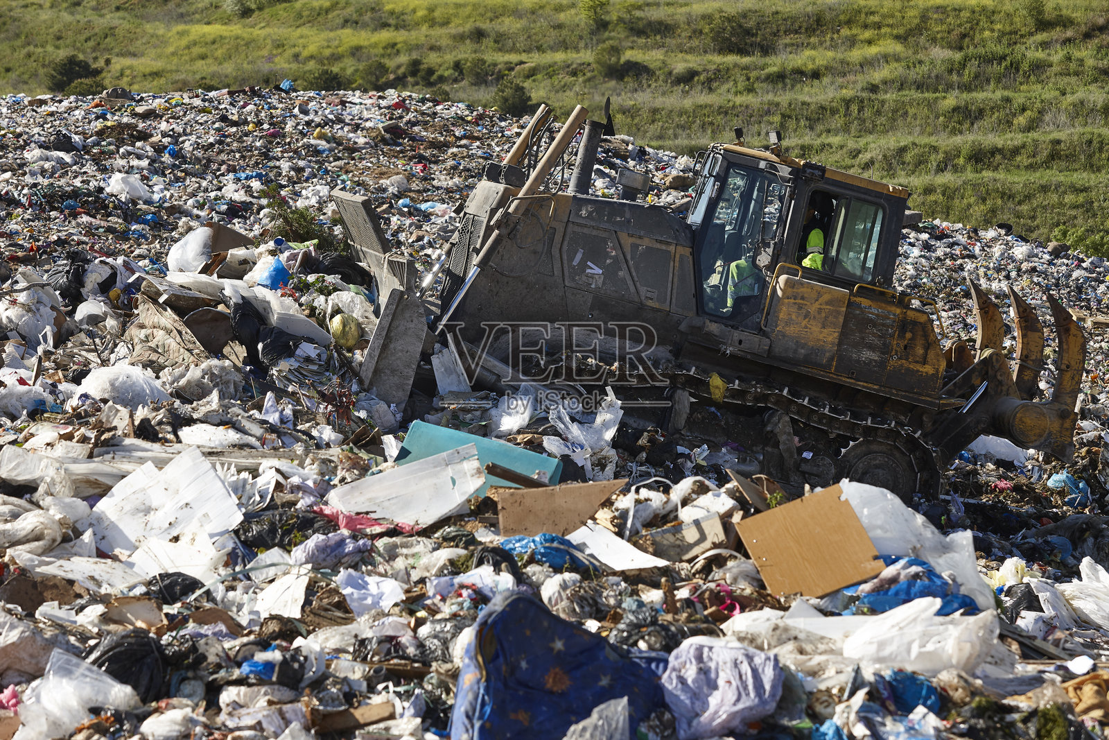 重型机械在露天垃圾填埋场粉碎垃圾。污染照片摄影图片