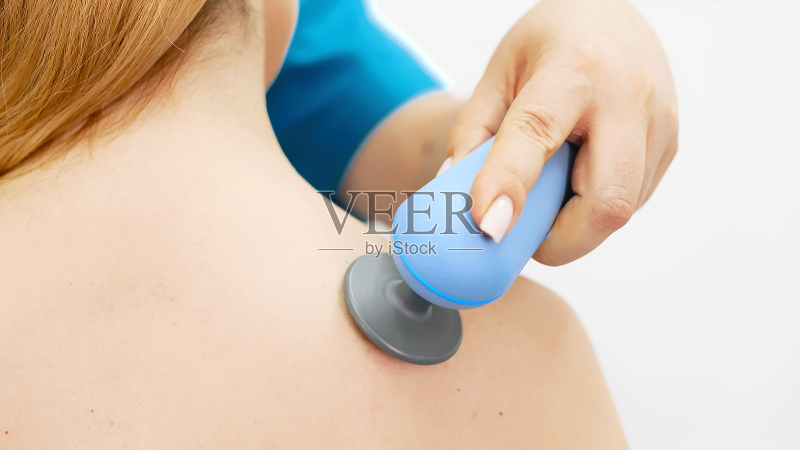 一位年轻女子在一家现代诊所接受电磁疗法。这种治疗可以促进组织愈合，减轻疼痛，加速肌肉恢复，促进整体健康。照片摄影图片