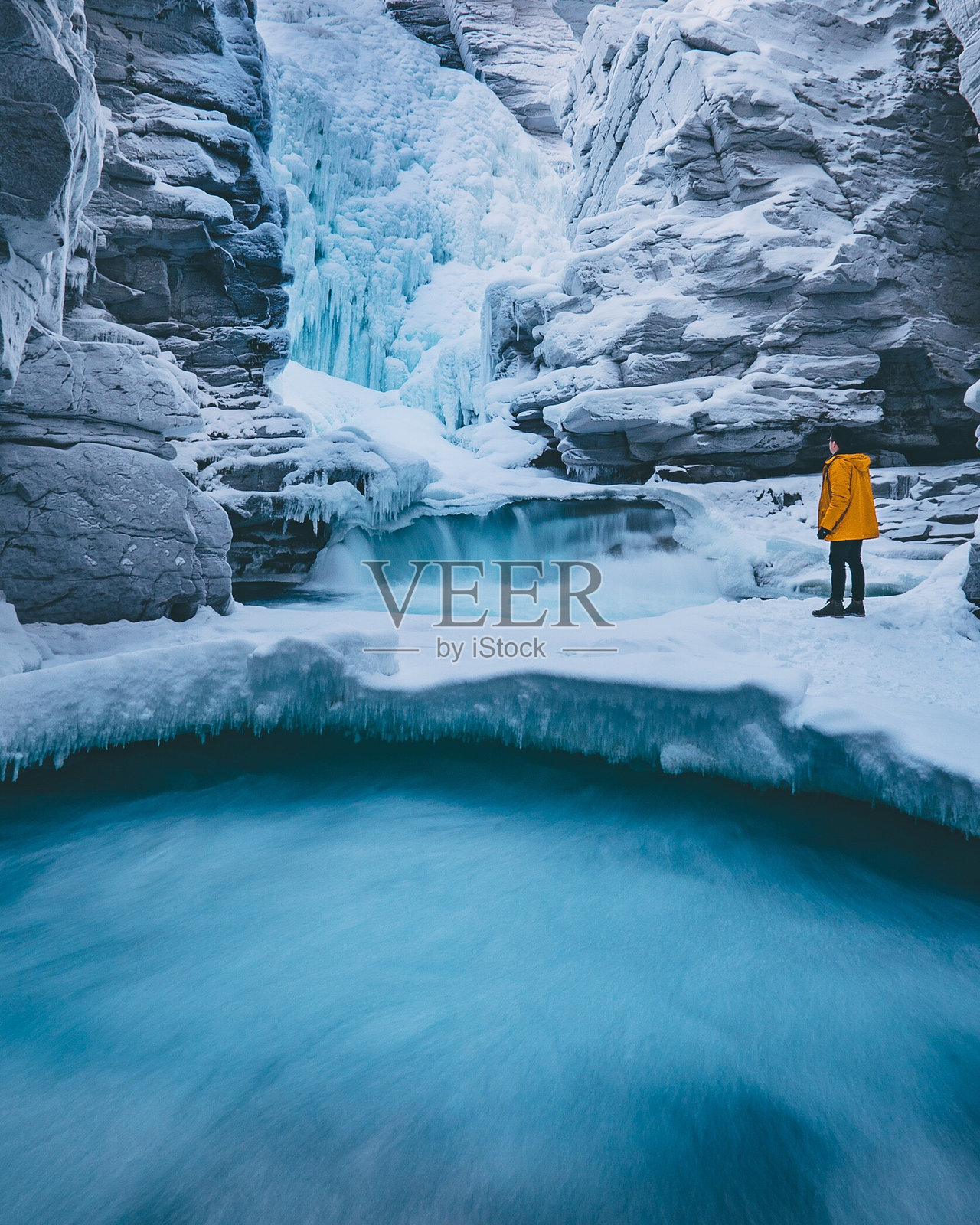 站在冰冻瀑布旁的年轻人的侧视图照片摄影图片