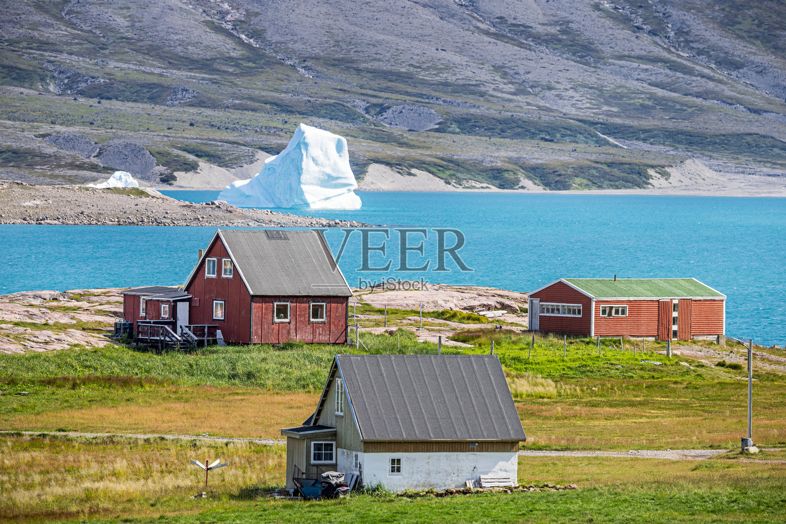 一座大冰山前的农场建筑照片摄影图片
