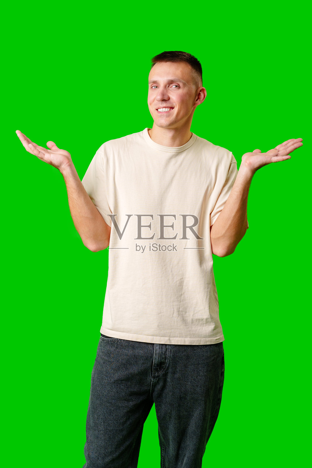 在明亮的绿色背景下，表情中性的年轻人耸了耸肩照片摄影图片