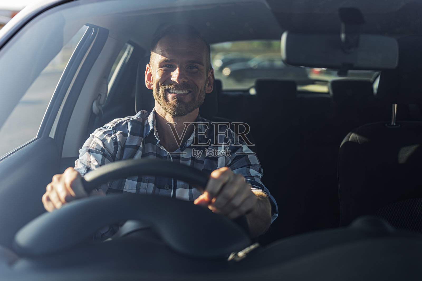 司机是一个年轻英俊的男子开着一辆车。照片摄影图片