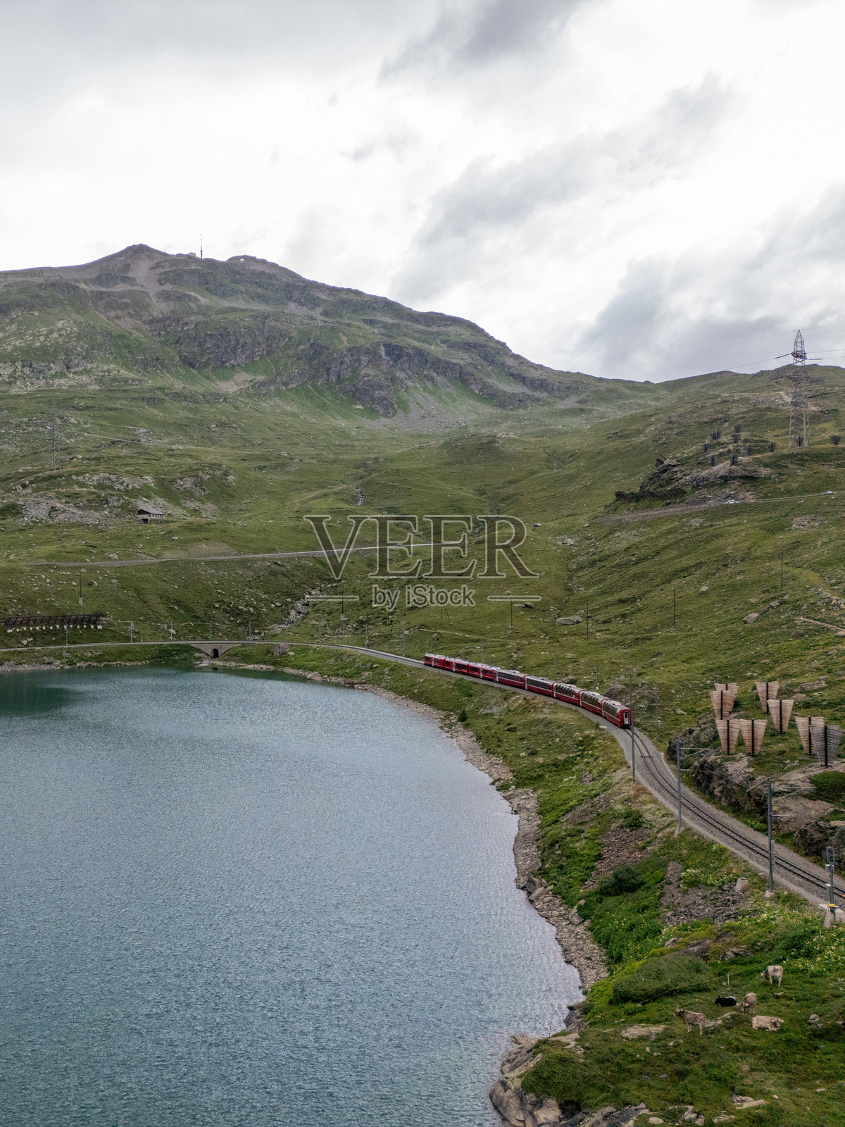 红色列车在阴天沿着山湖转弯照片摄影图片