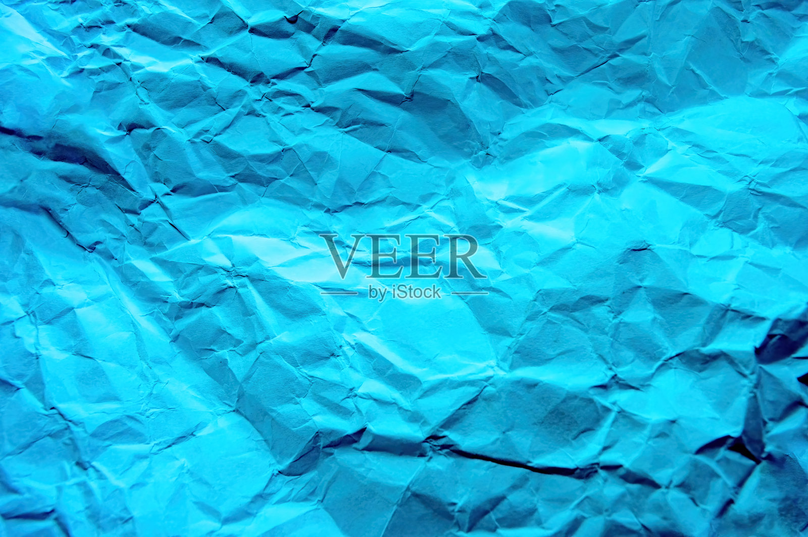 一张皱巴巴的蓝色纸的抽象图案。照片摄影图片