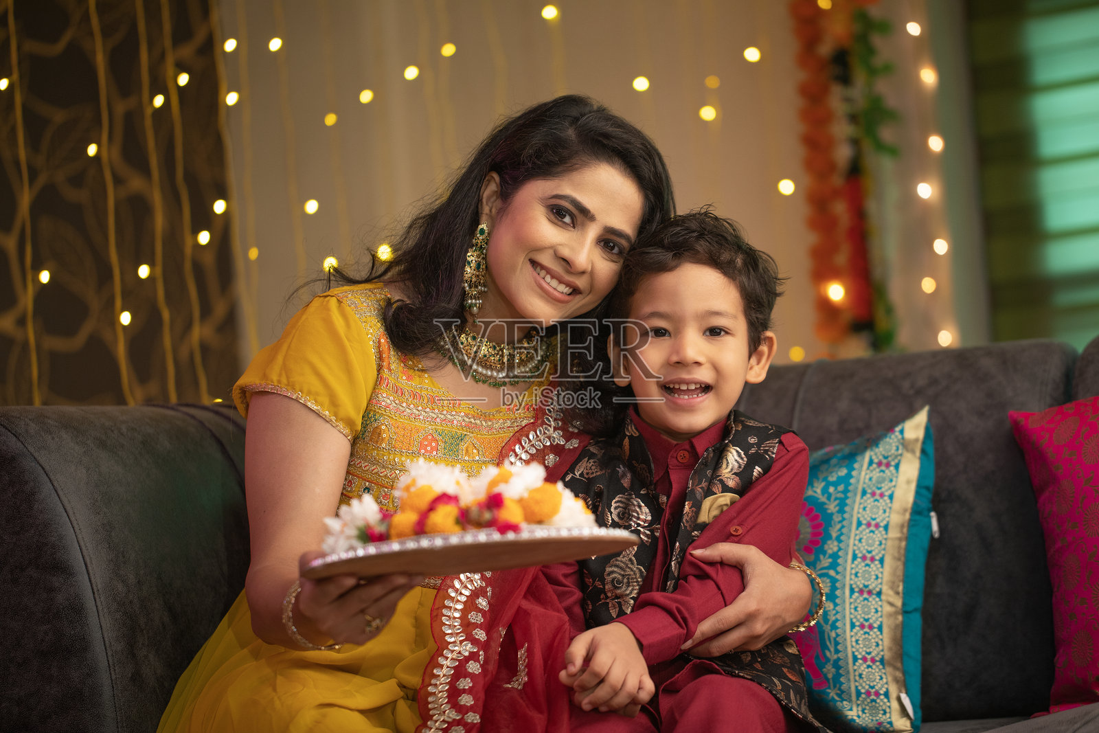 快乐的母子带着花环坐在家里的沙发上照片摄影图片