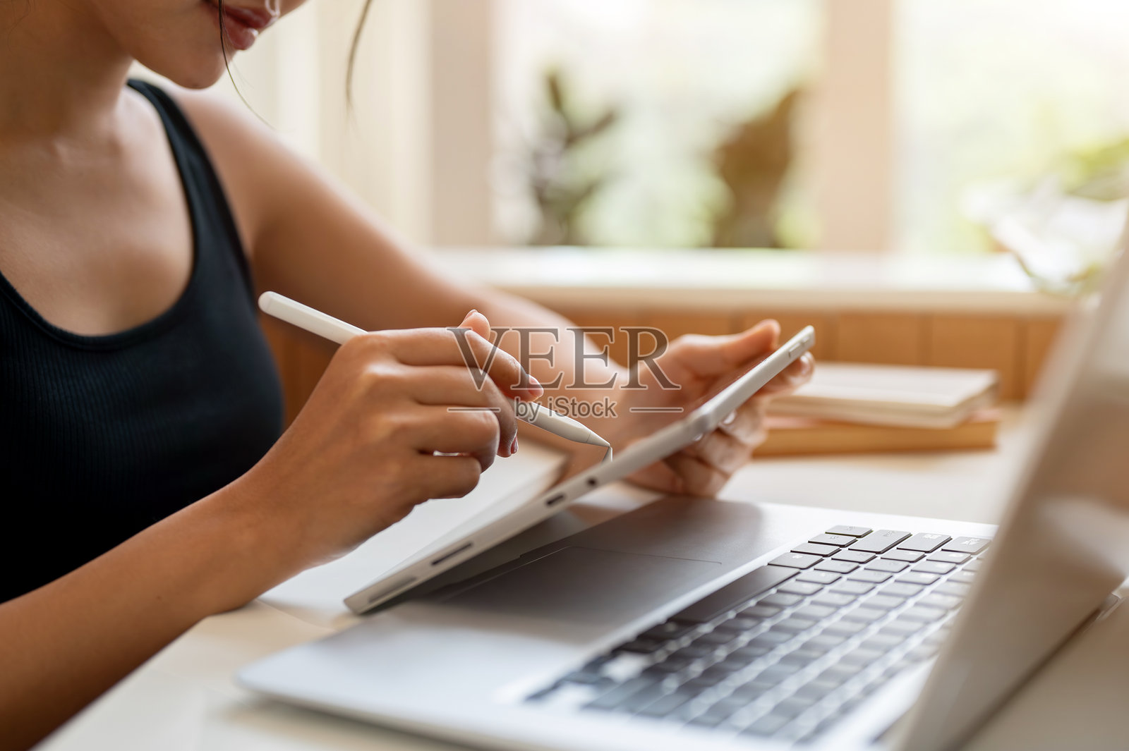 这张裁剪过的侧视图显示，一名女子在咖啡店用她的数码平板电脑远程工作。照片摄影图片