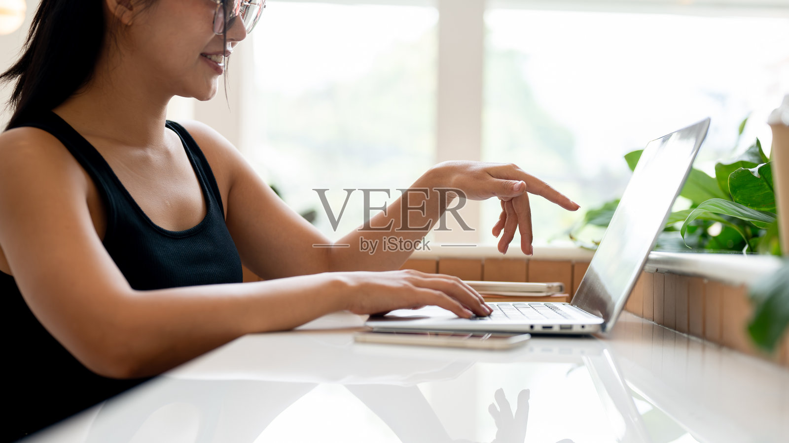 一位迷人的亚洲女性在咖啡店远程办公，用笔记本电脑工作。照片摄影图片