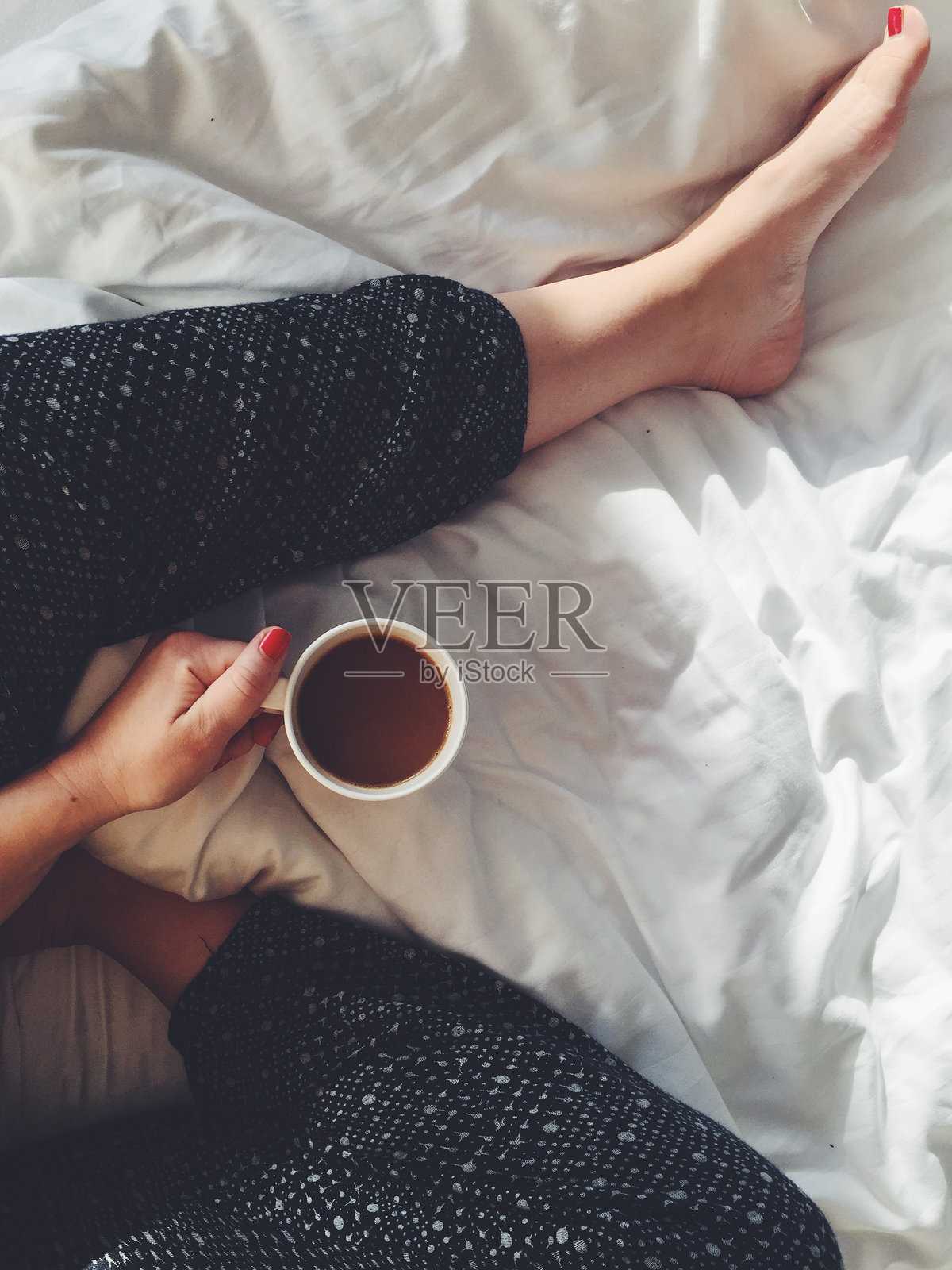 床上拿着咖啡杯的女人的低剖面照片摄影图片