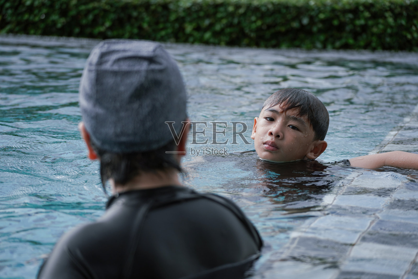 老年女性在游泳池里教男孩游泳照片摄影图片