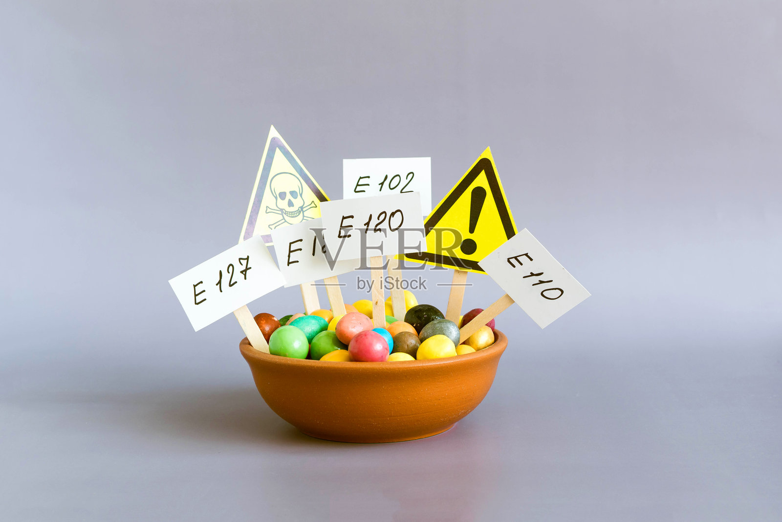 一个有各种食品添加剂和警告标志的杯子，特写在浅色背景上。照片摄影图片
