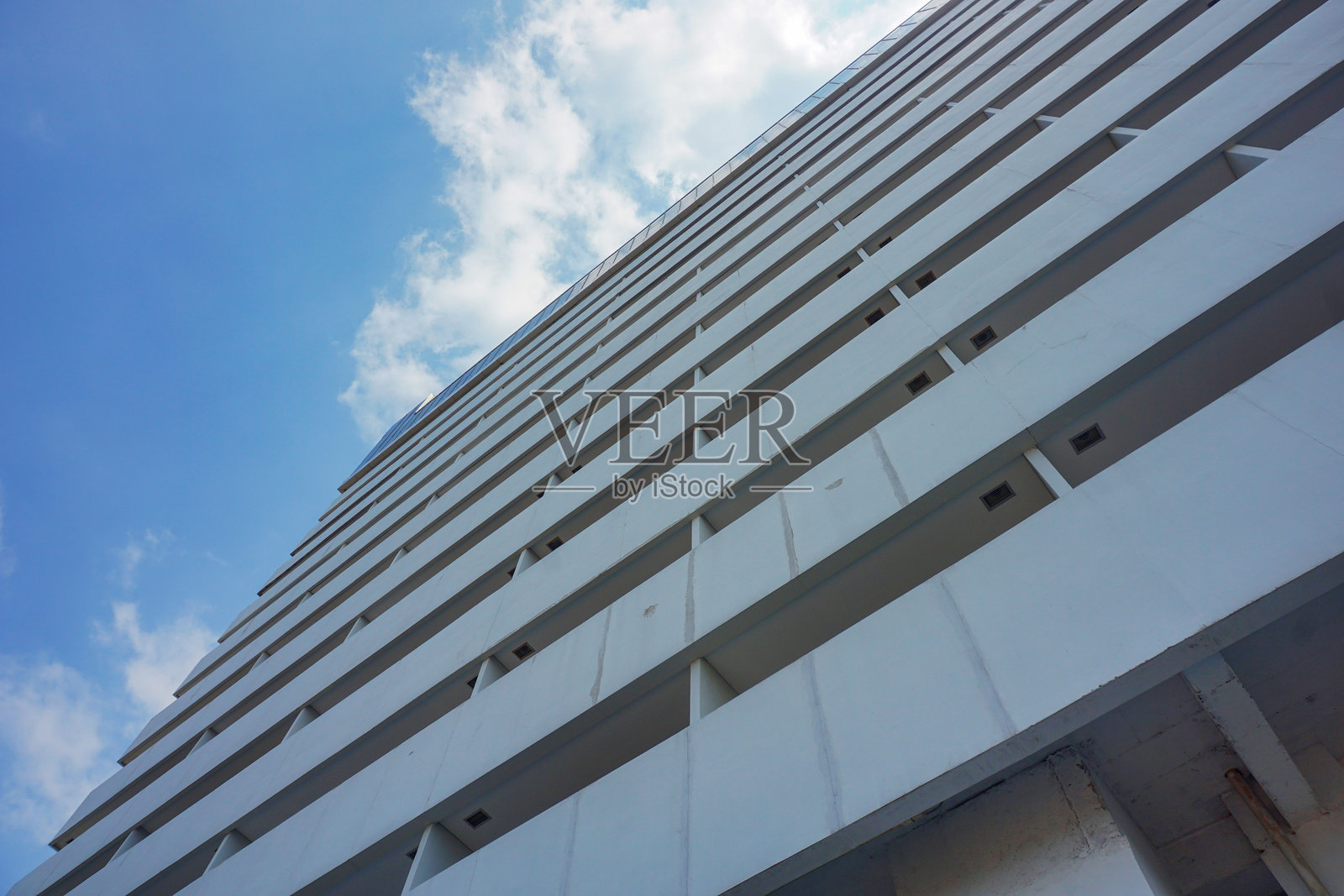 从一栋高层建筑下面，背景是多云的蓝天。照片摄影图片