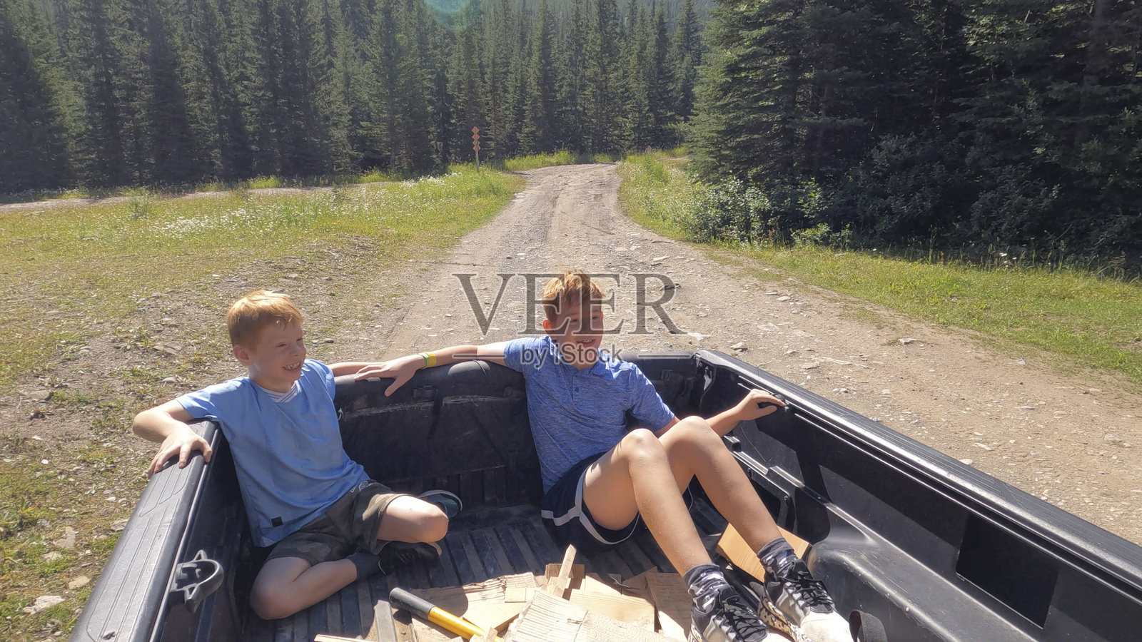 年轻男孩在皮卡车后面旅行，加拿大落基山脉照片摄影图片