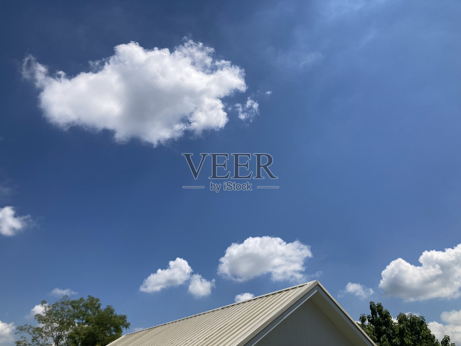 白色屋顶的房子，映衬着明亮的天空和美丽的蓬松白云照片摄影图片