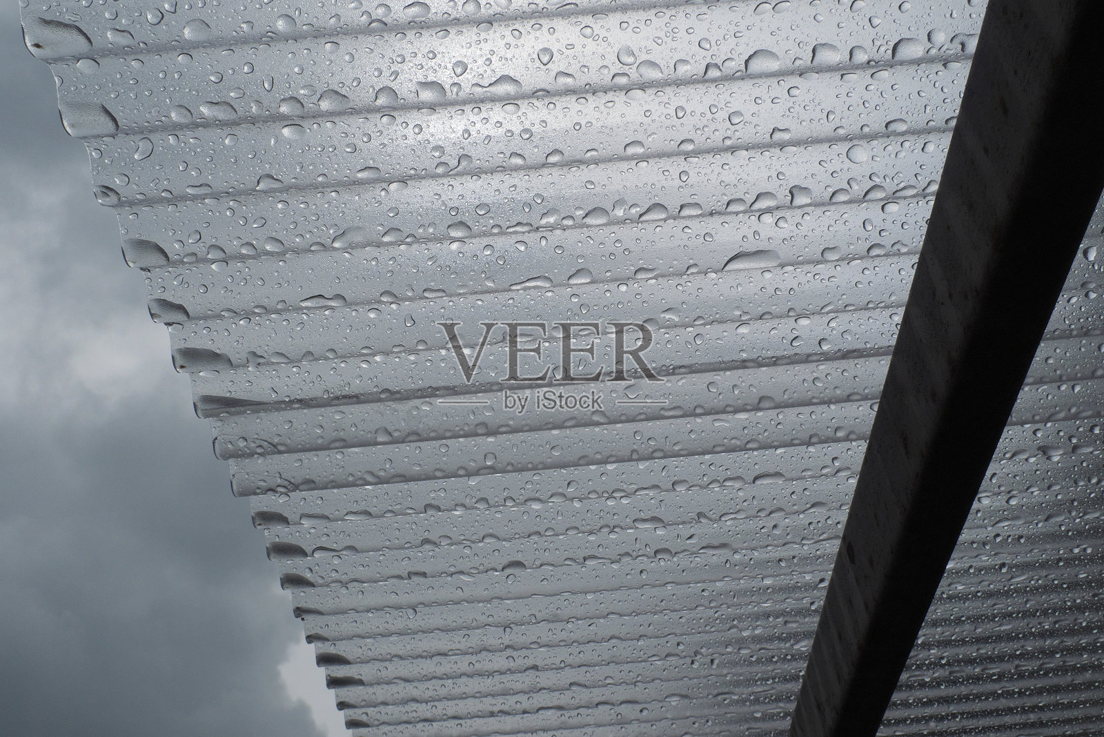 波纹塑料屋顶和水滴，背景是多云的天空照片摄影图片
