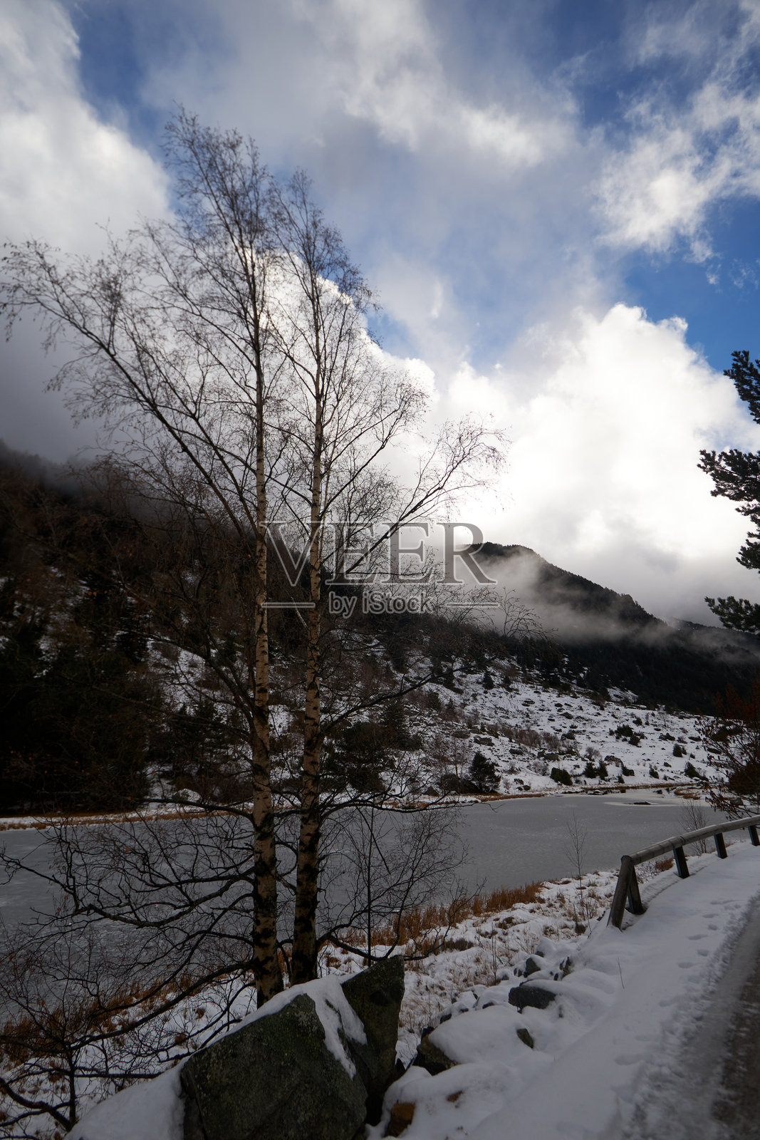 一片冰冻的湖泊位于被雪覆盖的山脉之下照片摄影图片