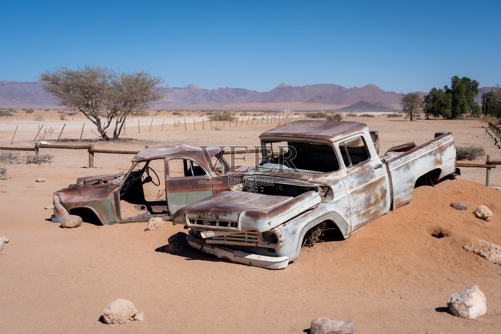 两辆旧的废弃汽车，半埋在沙漠沙子里照片摄影图片