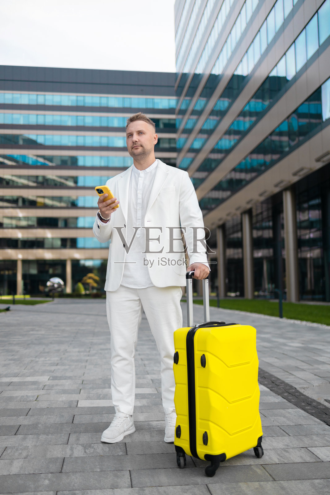 专注的年轻企业员工投资者在商业中心附近走动并使用手机。照片摄影图片