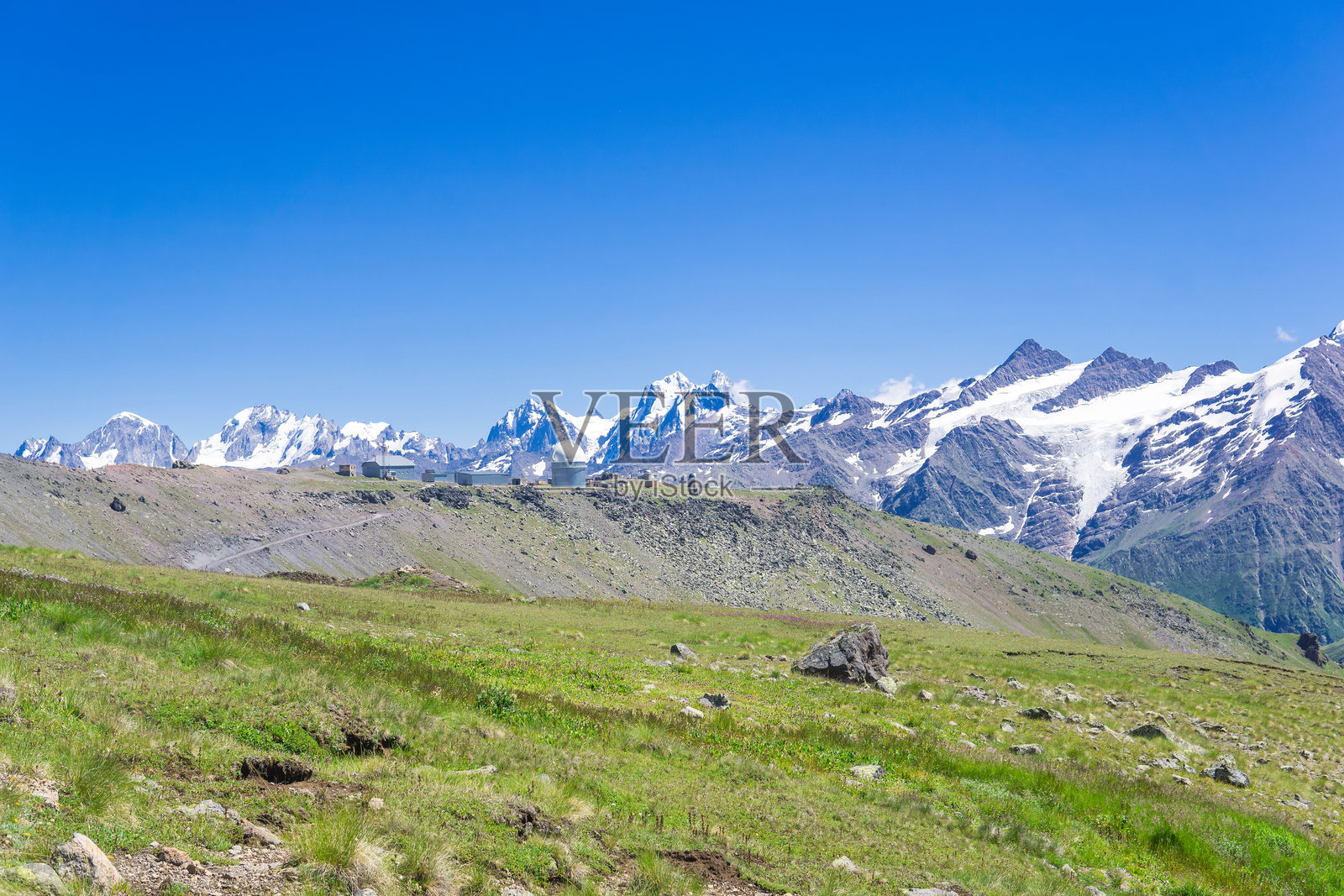 mountain landscape with alpine meadow, observatory in the distance and mountain peaks in the background照片摄影图片