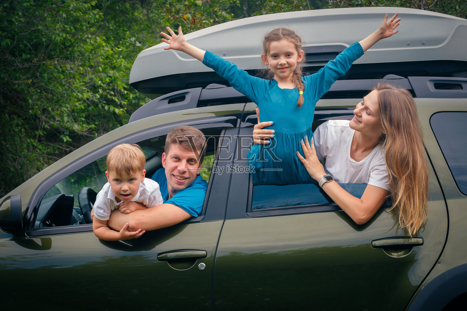 一个快乐的家庭在美丽的大自然中，愉快地享受着刺激的户外冒险，坐在他们的车里。照片摄影图片