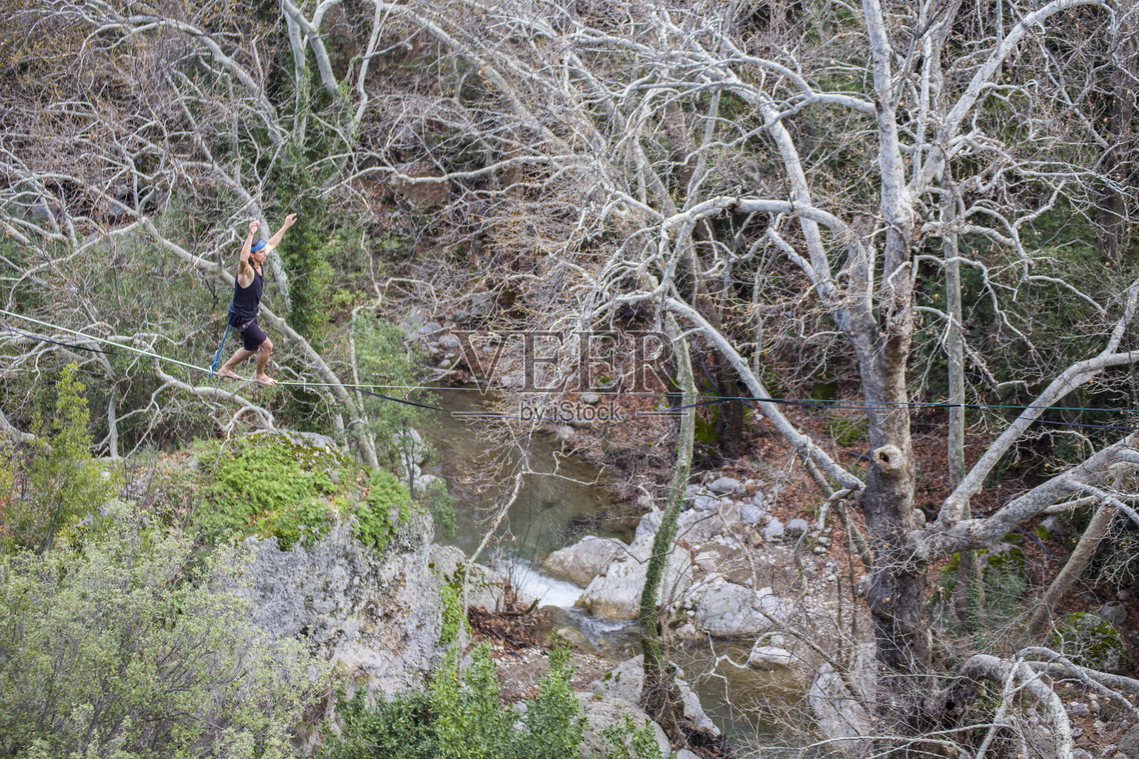 走钢丝的人在峡谷上方的绳索上行走。照片摄影图片
