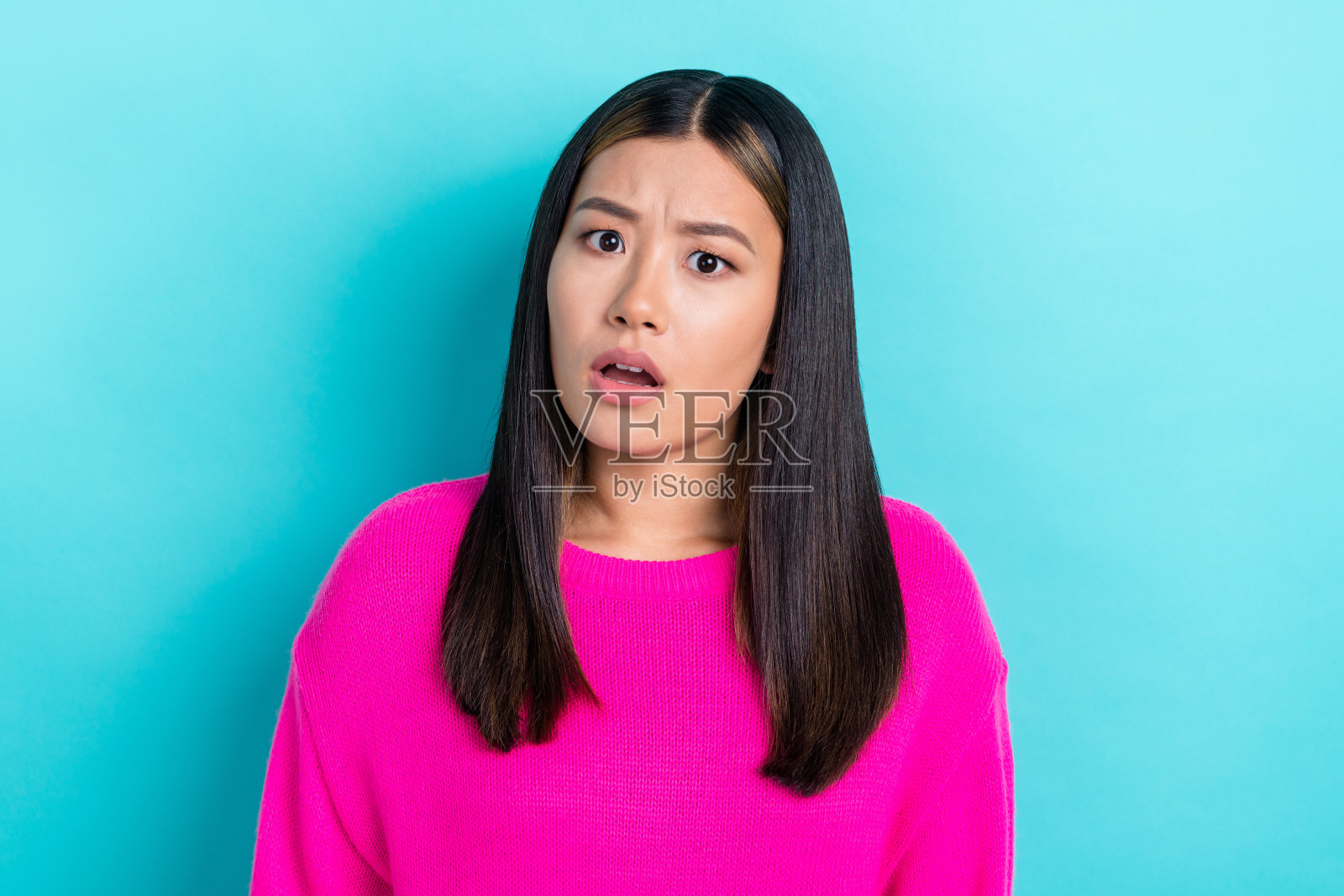 年轻的可爱日本女士，面露困惑和不满，疑惑地盯着你，背景为蓝色。照片摄影图片