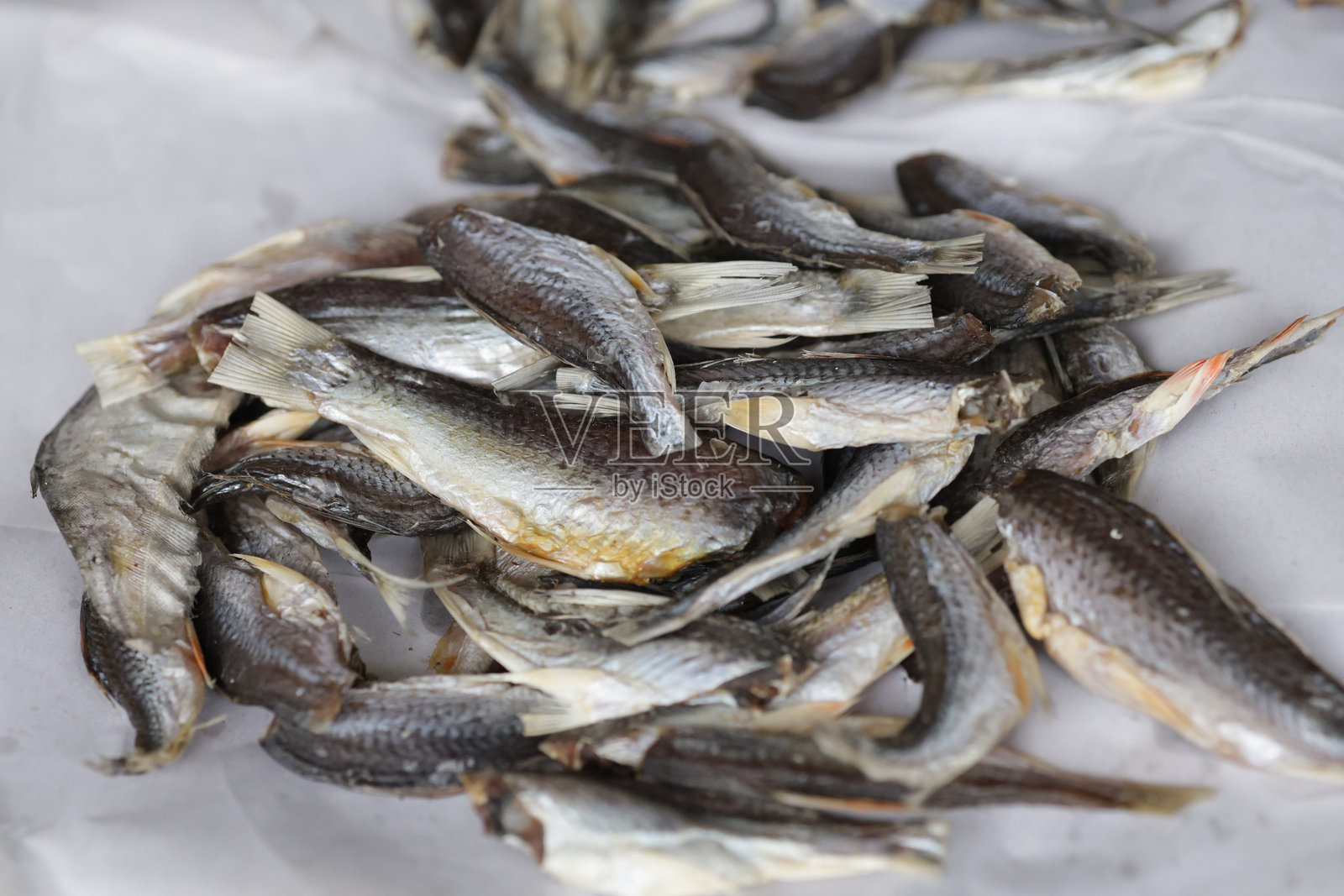 干鱼堆放在白纸上。干鱼是钙的良好来源。照片摄影图片
