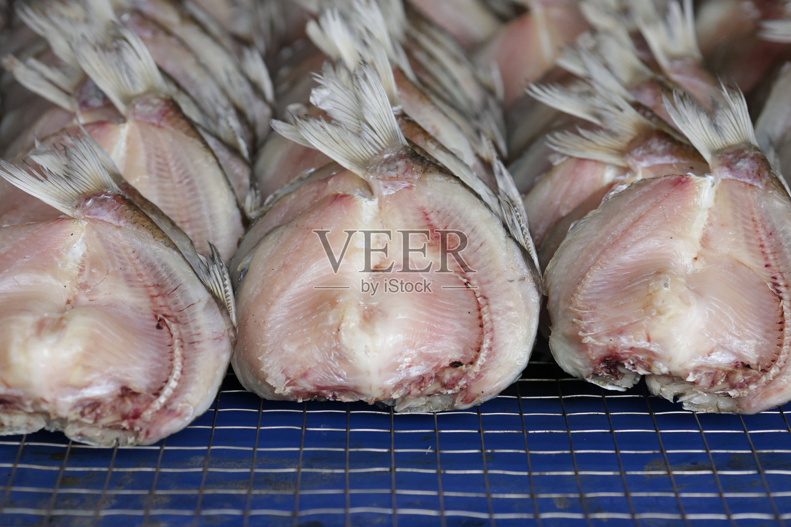 干鱼整齐地堆放在一个网格上，供市场销售。照片摄影图片