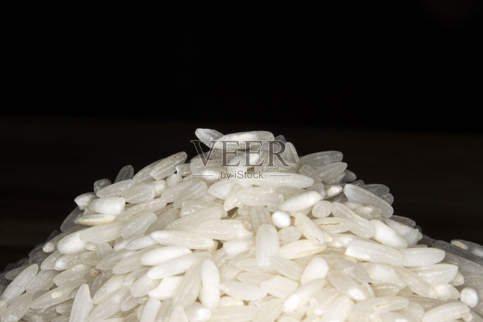 一堆生白米在黑色背景上，留有空白空间。照片摄影图片