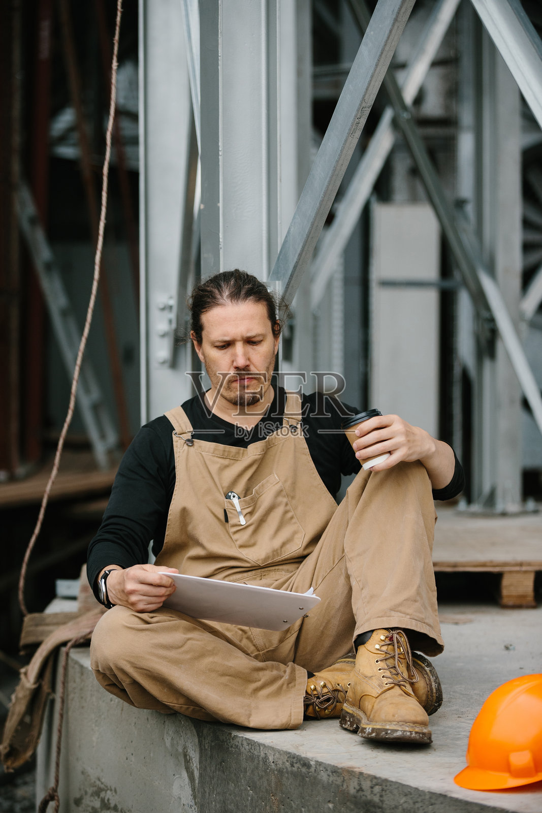 一名工人在建筑工地上休息，享受咖啡时间。照片摄影图片