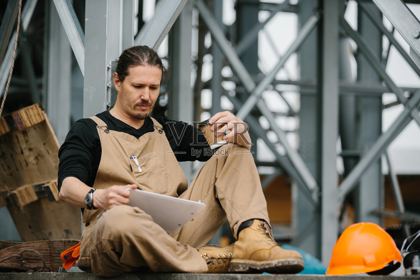 一名工人在建筑工地上休息，享受咖啡时间。照片摄影图片