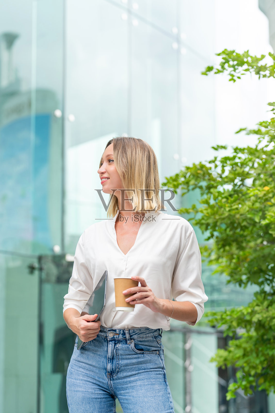 白人女性在城市环境中手持平板电脑和咖啡杯照片摄影图片