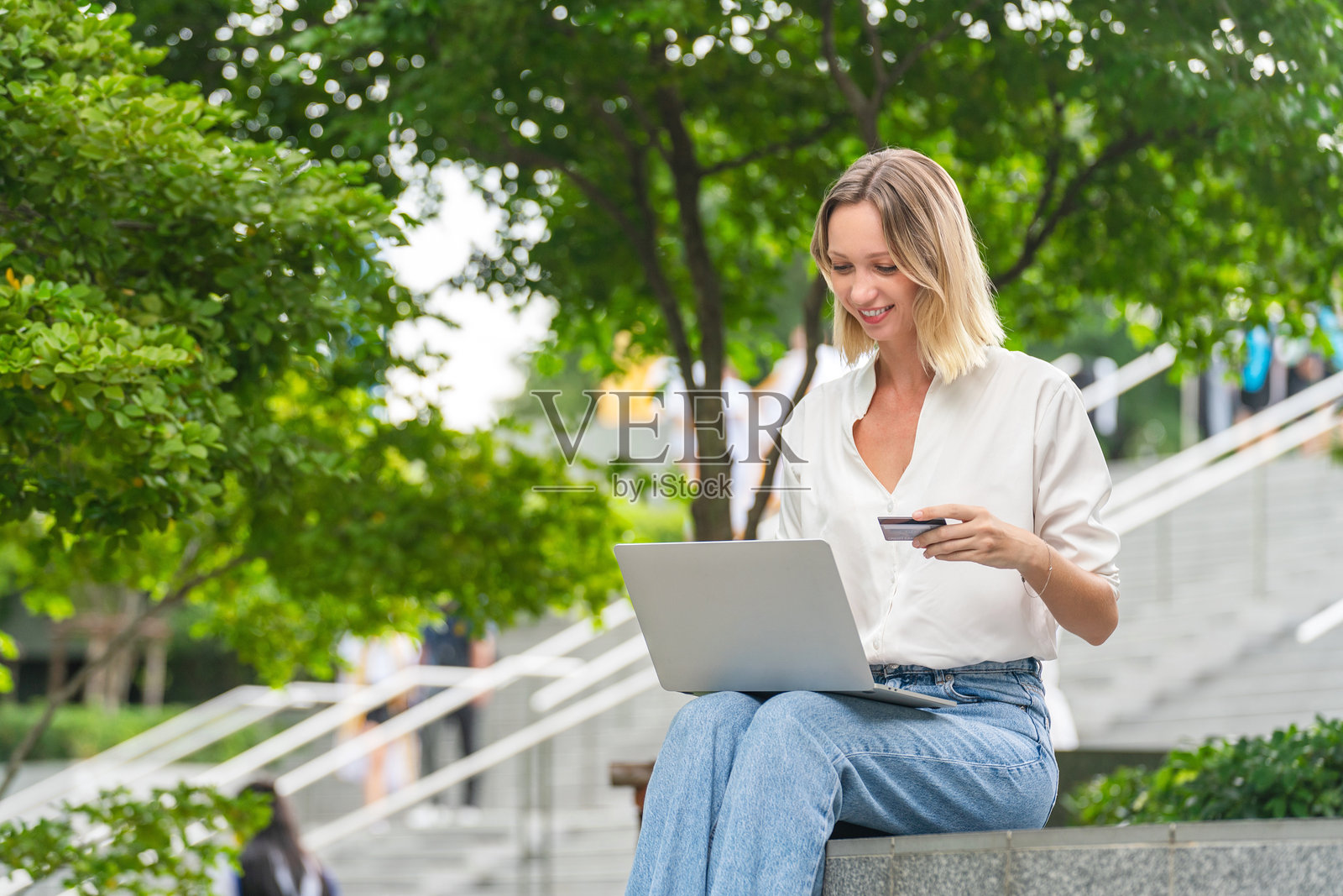 女性在户外使用笔记本电脑和信用卡进行在线支付照片摄影图片