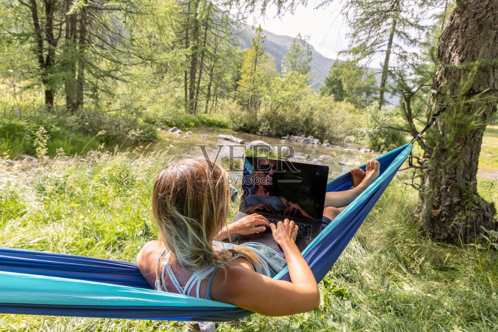 在森林吊床上放松时使用笔记本电脑的女性照片摄影图片