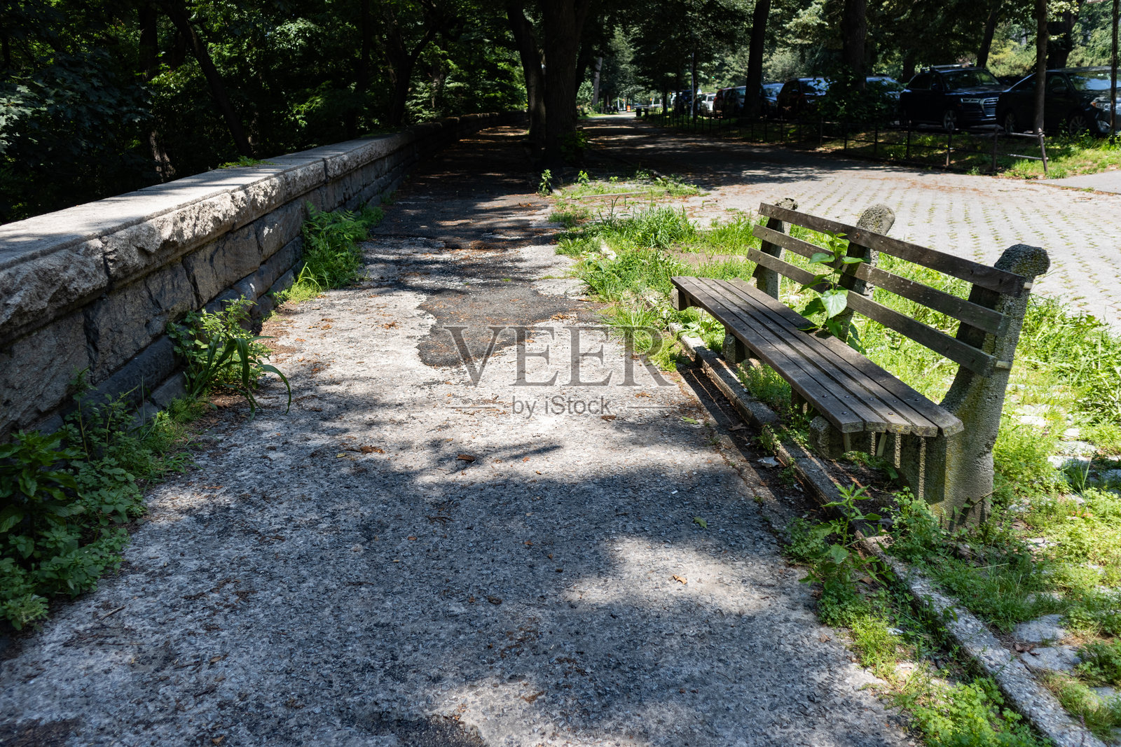 夏季时节，纽约市上西区河滨公园旁边的破旧人行道上的空长椅照片摄影图片