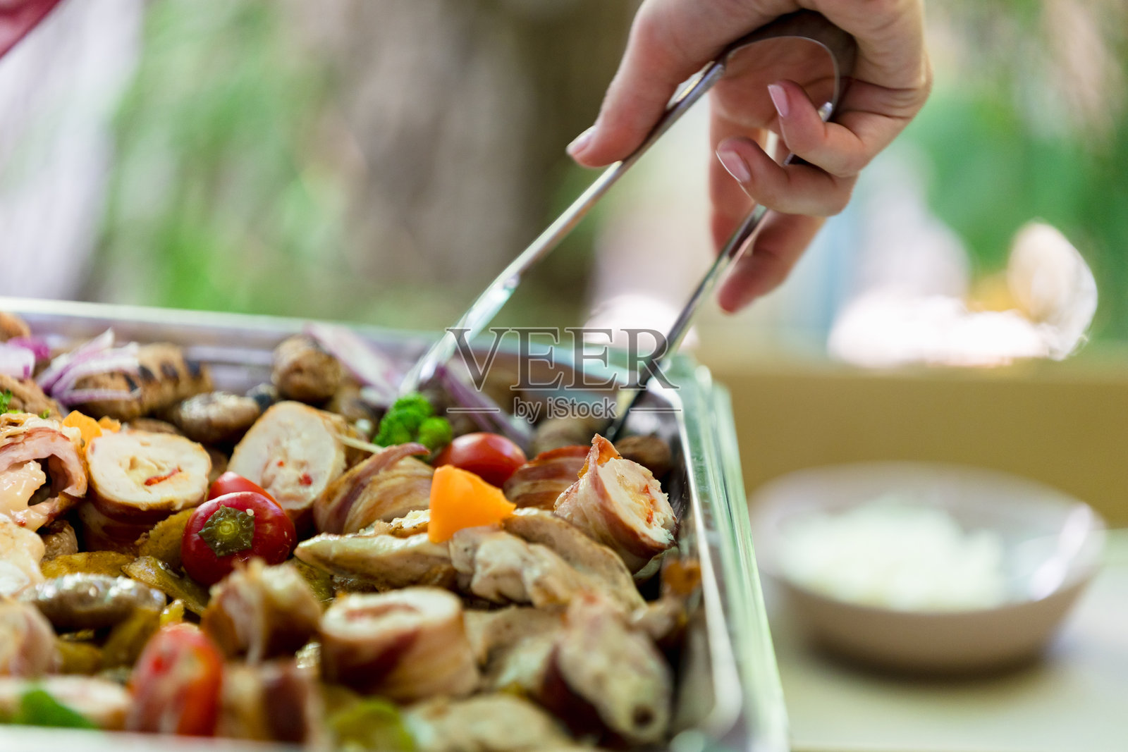 一只手在夏季花园聚会上端上美味的烤蔬菜和调味鸡肉照片摄影图片