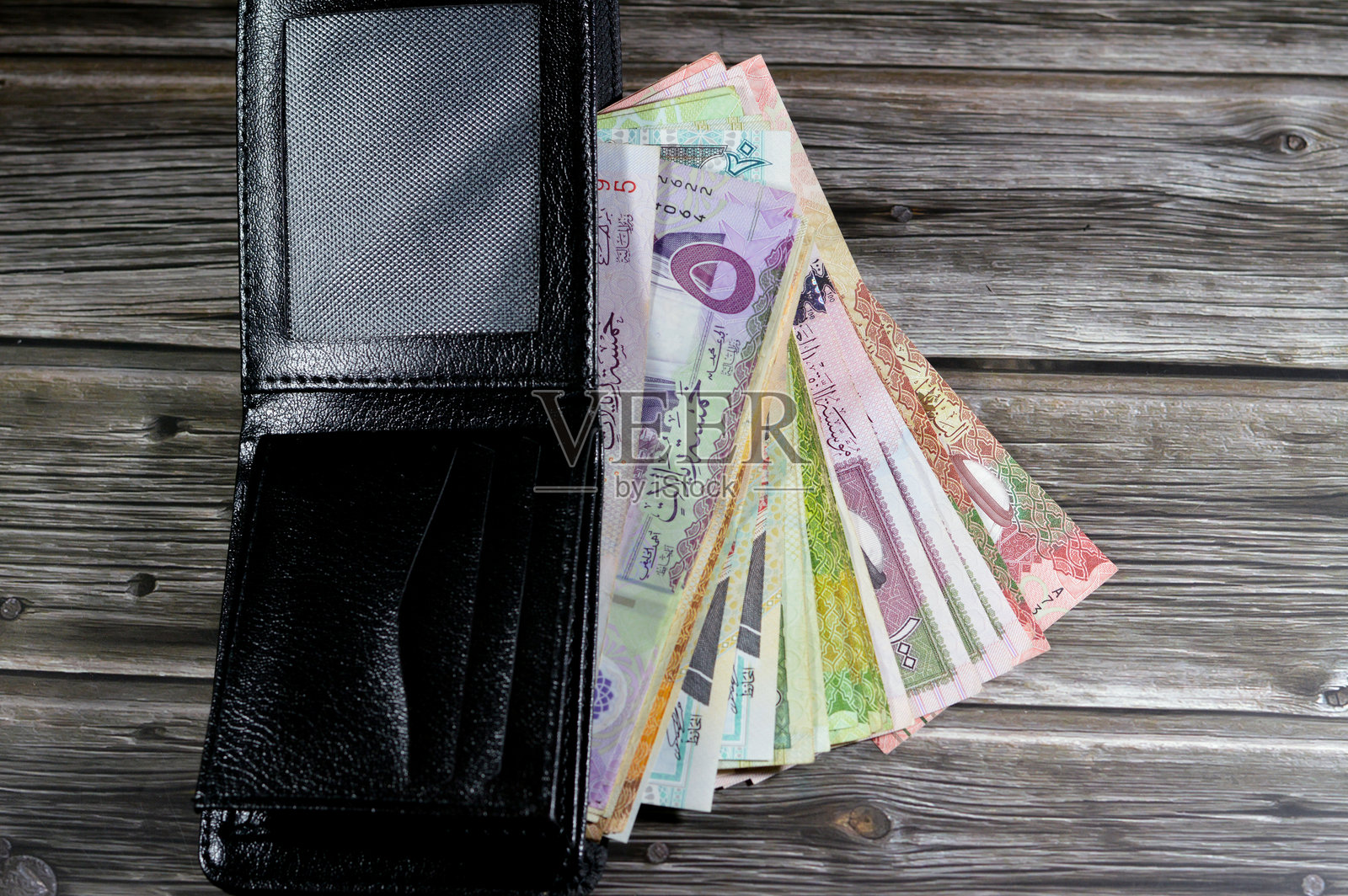 沙特阿拉伯里亚尔钞票，黑色皮革钱包中的一堆沙特里亚尔现金，购买、销售、交易、金钱和经济状况照片摄影图片