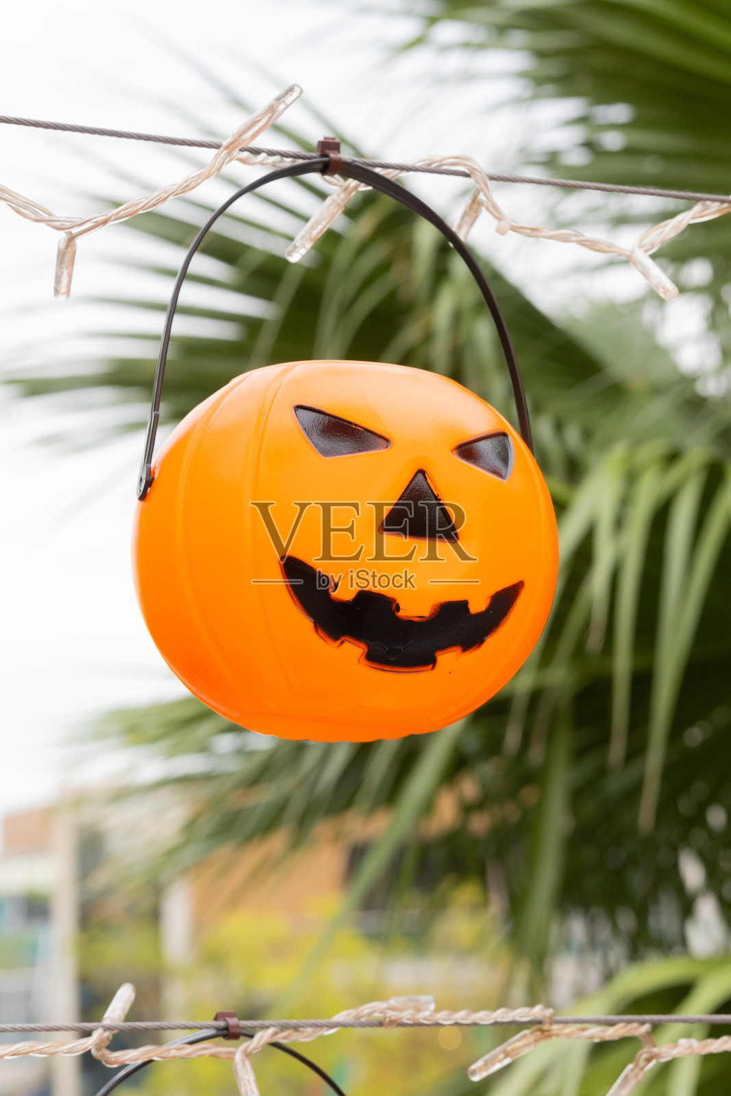 户外挂着万圣节灯饰的塑料南瓜糖果桶照片摄影图片