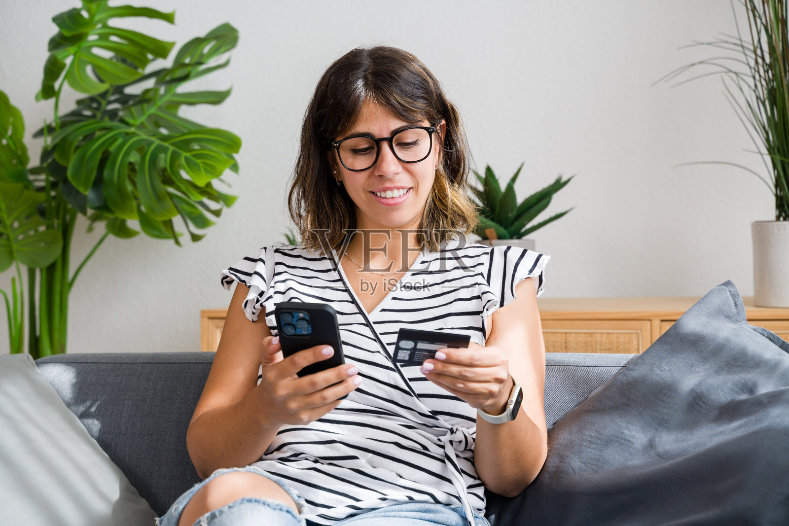 微笑的女性在家中使用智能手机和信用卡进行在线购物照片摄影图片