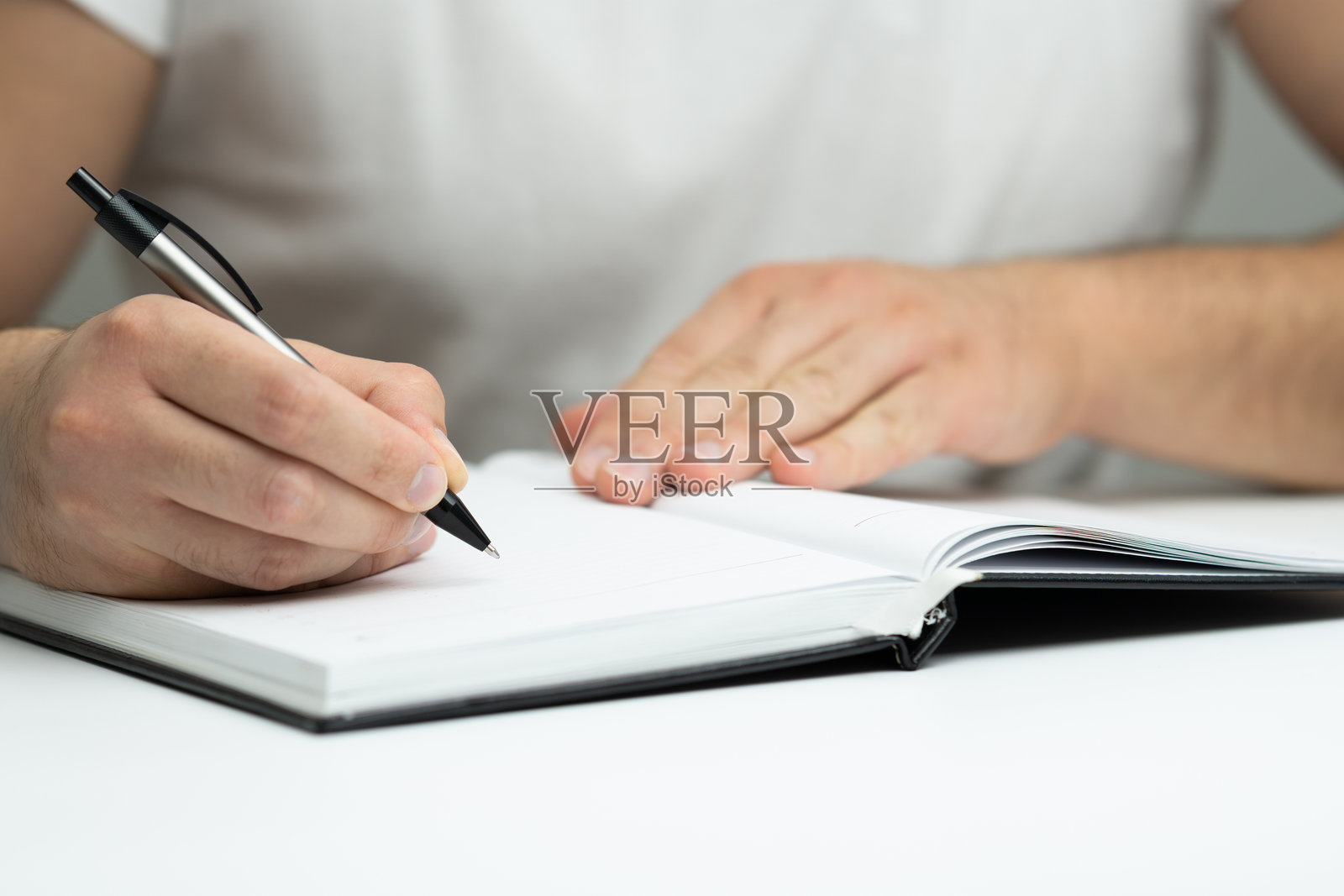 年轻男子在笔记本上手写的特写镜头照片摄影图片