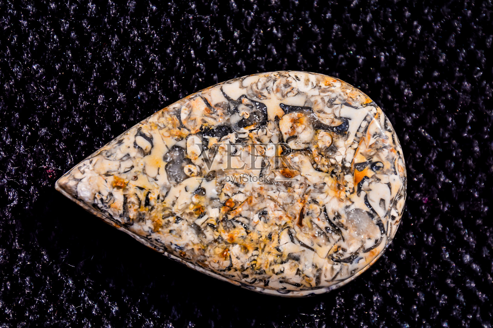 一颗小巧圆润的棕白色石头，背景为黑色照片摄影图片