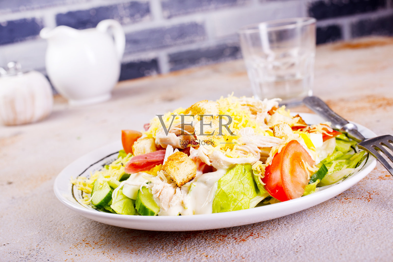 圆盘上摆放着鸡肉凯撒沙拉、生菜、土豆和面包，背景为浅色。照片摄影图片