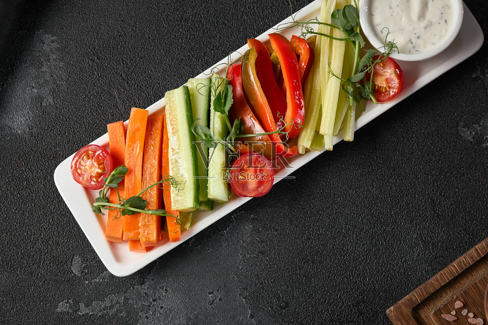 色彩鲜艳的蔬菜拼盘，新鲜健康的搭配，配有蘸酱，背景为纹理黑色。照片摄影图片