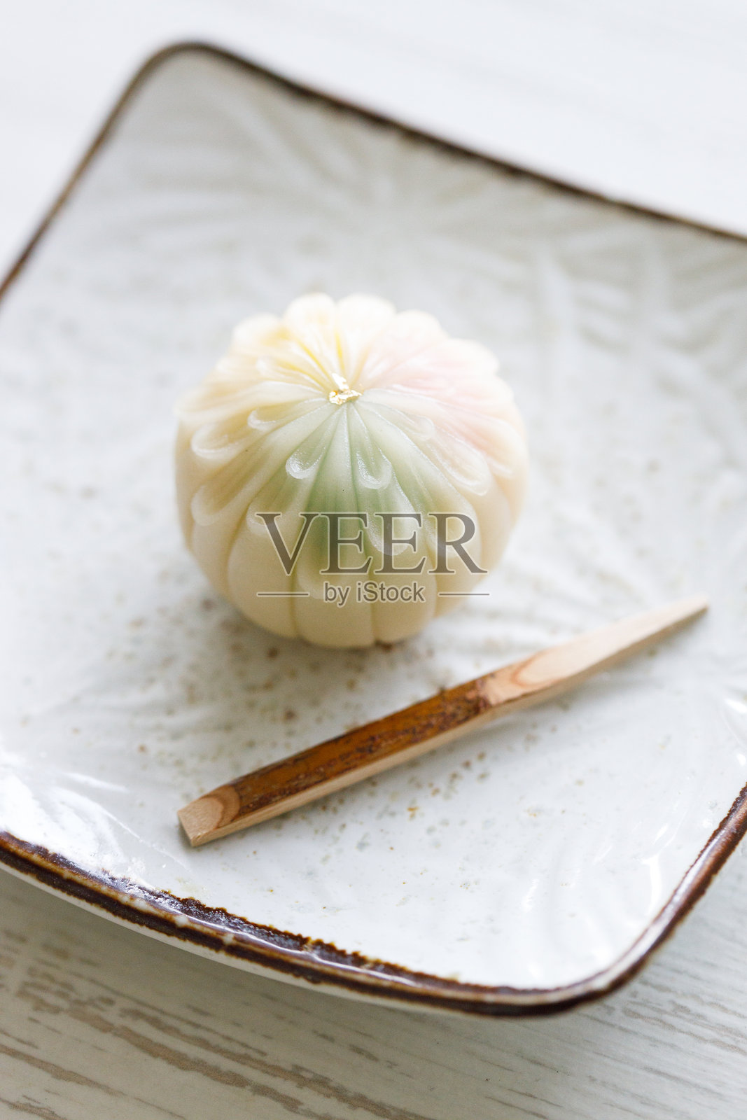 一块美味的日本点心放在白色陶瓷盘上，置于白色木桌上。选择性对焦。照片摄影图片