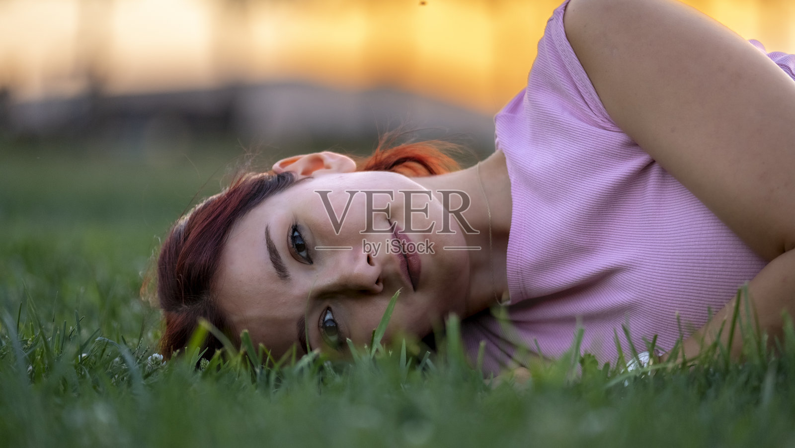 一位美丽的红发年轻女性在夏日的公园中时尚地展示自己，穿着夏季连衣裙摆姿势。照片摄影图片